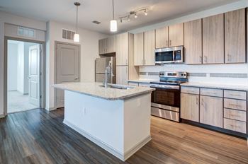 A kitchen with a large island and wooden floors and cabinets